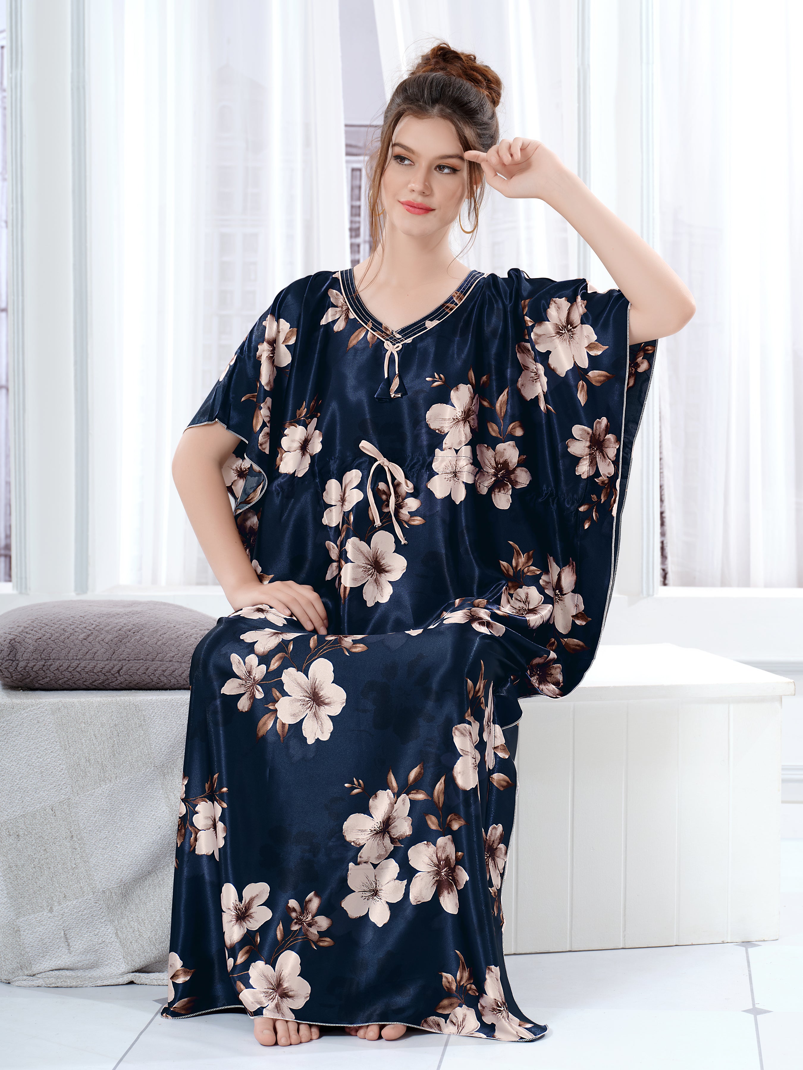 Woman sitting wearing a navy blue floral satin kaftan for women with drawstring waist.