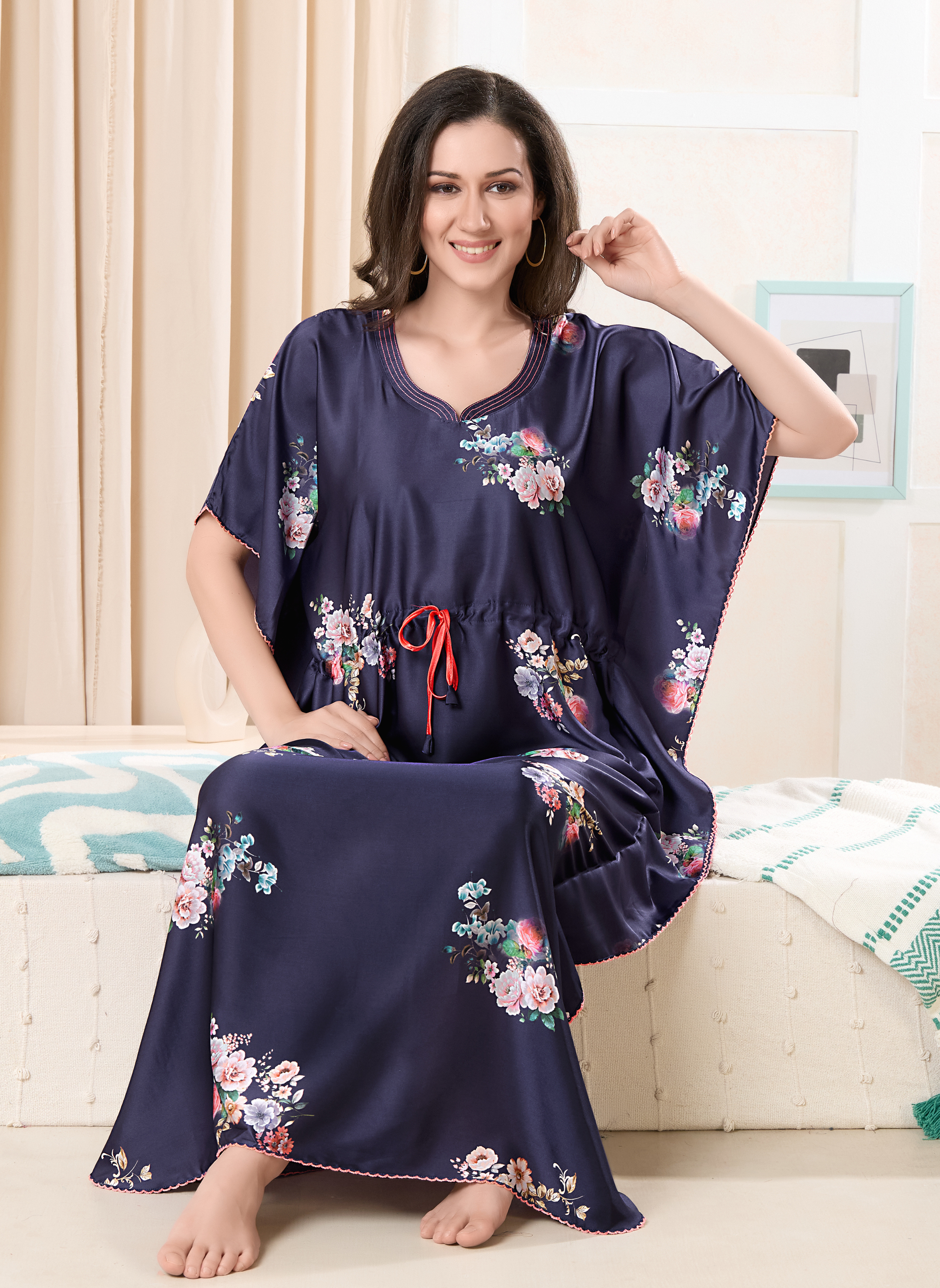 Model sitting wearing navy blue satin kaftan for women with floral print and red drawstring waist