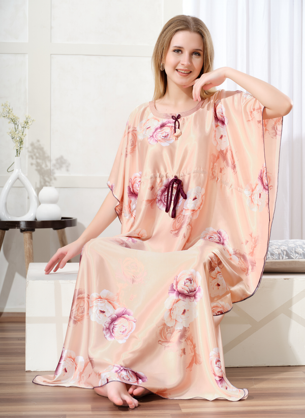 Model sitting wearing pastel peach satin kaftan for women with floral print and plum drawstring waist