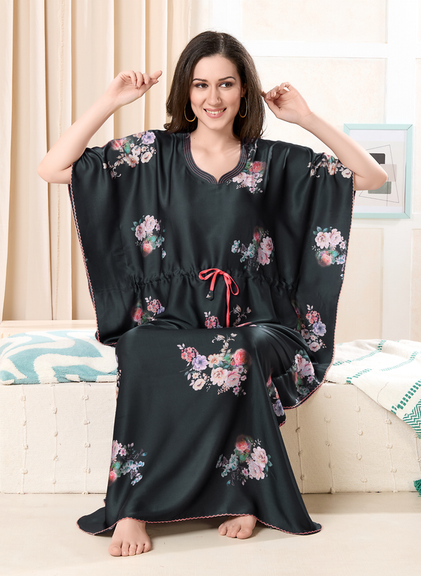 Model sitting wearing black satin kaftan for women with floral print and pink drawstring waist