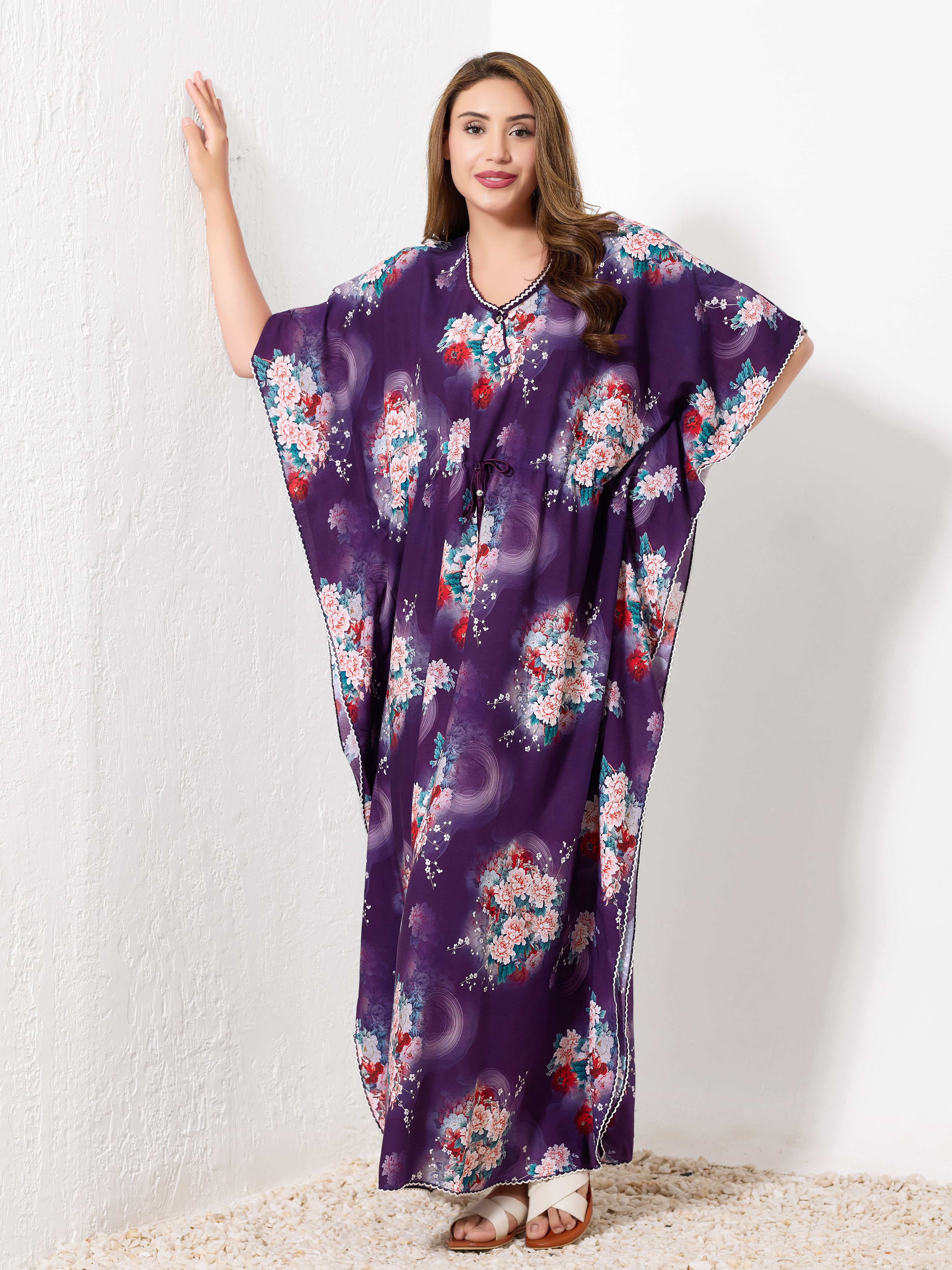 Model standing against white wall wearing purple premium cotton kaftan for women with vibrant floral print