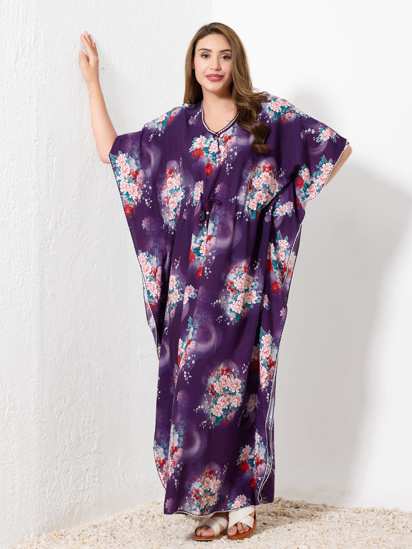 Model standing against white wall wearing purple premium cotton kaftan for women with vibrant floral print