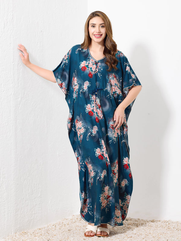 Model standing against white wall wearing teal blue premium cotton kaftan for women with vibrant floral print